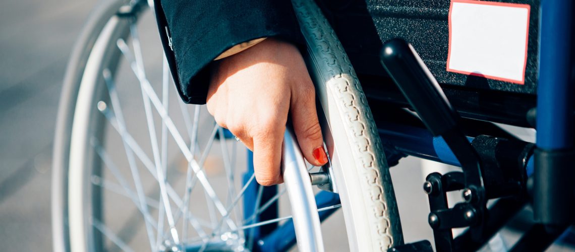close up of a female hand holding a wheelchair - life with a disabilty concept