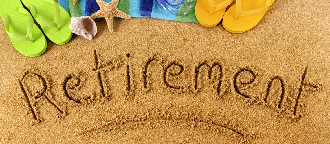 The word Retirement written on a sandy beach, with scuba mask, beach towel, starfish and flip flops.